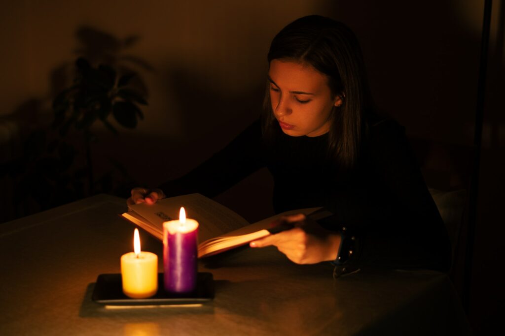 Young woman reading by candlelight. Blackout concept, power cut